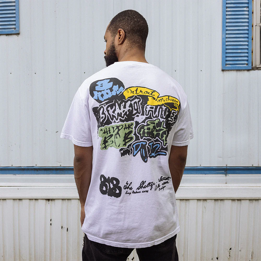 Man looking over his shoulder, showcasing the back of the 8 Mile Graffiti T-Shirt with colorful Detroit-inspired graffiti art and Eminem signatures - Exclusive Eminem Tee.