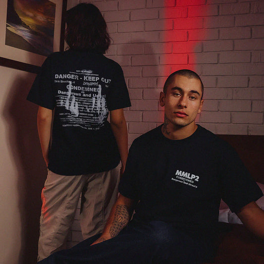 Male and female models wearing Eminem MMLP2 Condemned Anniversary T-Shirts, front simple logo and back featuring a condemned notice and song titles.