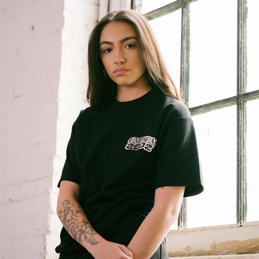 Model confidently wearing 'The Eminem Show Chrome Logo T-Shirt' in black, with a detailed chrome-like logo on the chest, highlighting a minimalist yet bold design.
