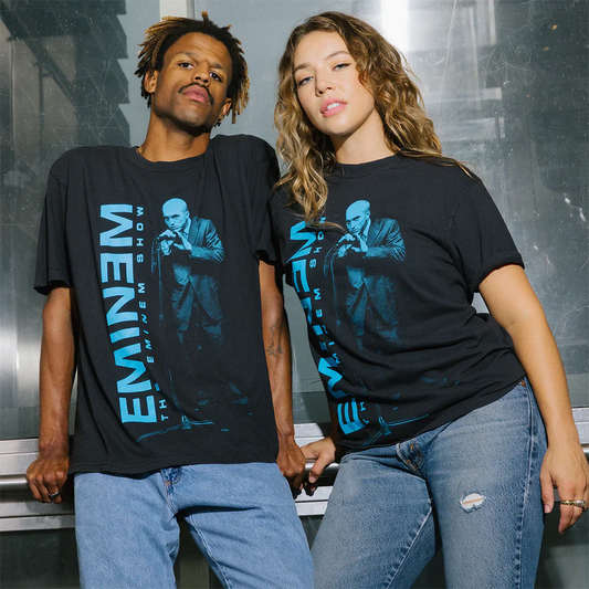 Two models pose in the Eminem Show 'On The Mic' T-Shirts, featuring a dynamic Eminem performance photo with a bold reversed name print.