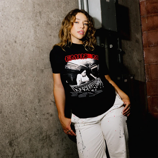 Model in a laid-back pose wearing the Eminem Show 20th Anniversary Studio T-Shirt, highlighting the album's studio scene in a striking red and black design.