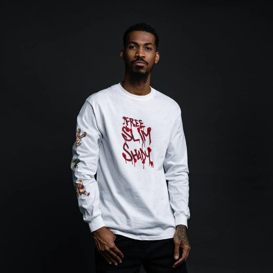 Male model wearing the 'Free Slim Shady' white long sleeve shirt with iconic red drip text on the front and illustrated sleeve detailing.