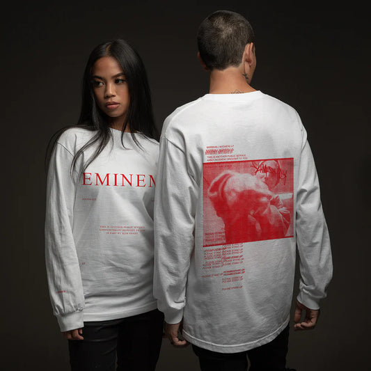 A man and woman duo modeling the 'MMLP PSA' white sweatshirt featuring bold 'EMINEM' print on the front and a vivid red graphic of Eminem with a public service announcement text on the back.