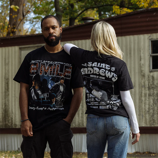 A couple stands together, the man in the 8 Mile 20th Anniversary T-shirt and the woman in the St. Andrews Event Black T-shirt, representing iconic moments from Eminem's career.
